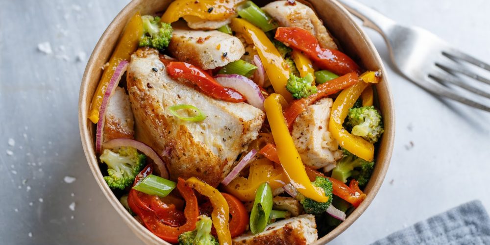 Noodles with chicken and vegetables served in lunch box on dark background. Zero waste