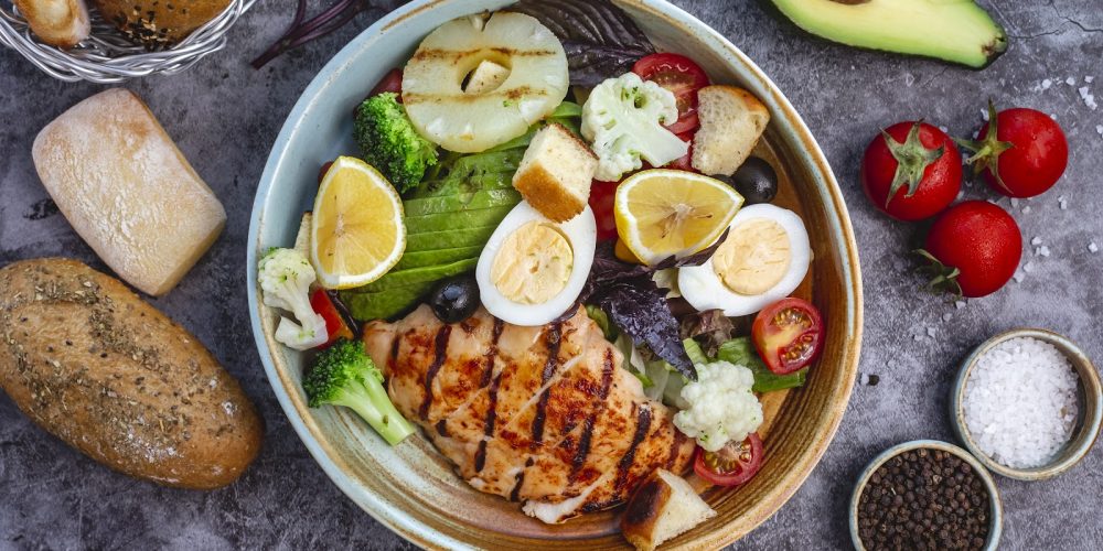 top view of healthy diet salad with grilled chicken broccoli cauliflower tomato lettuce avocado and lettuce